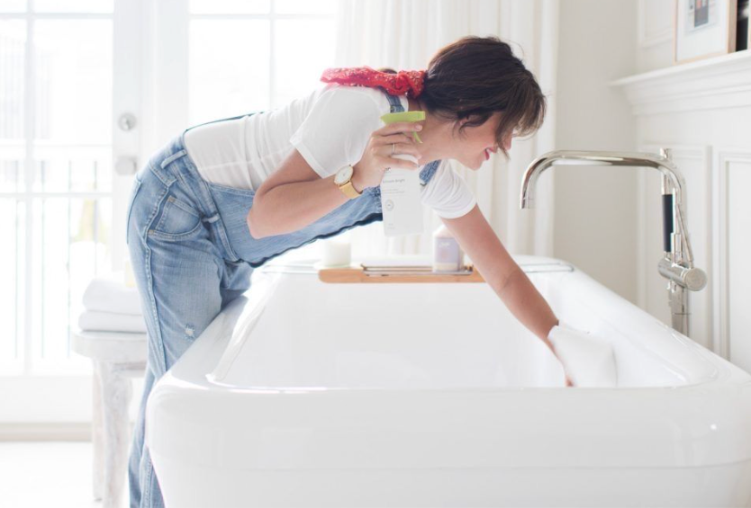 Woman cleaning the bathtub with spray bottle Residential Cleaning Services Day Clean