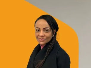 Photo portrait de Juliet, apprenante chez Konexio, posant devant un fond orange et gris.