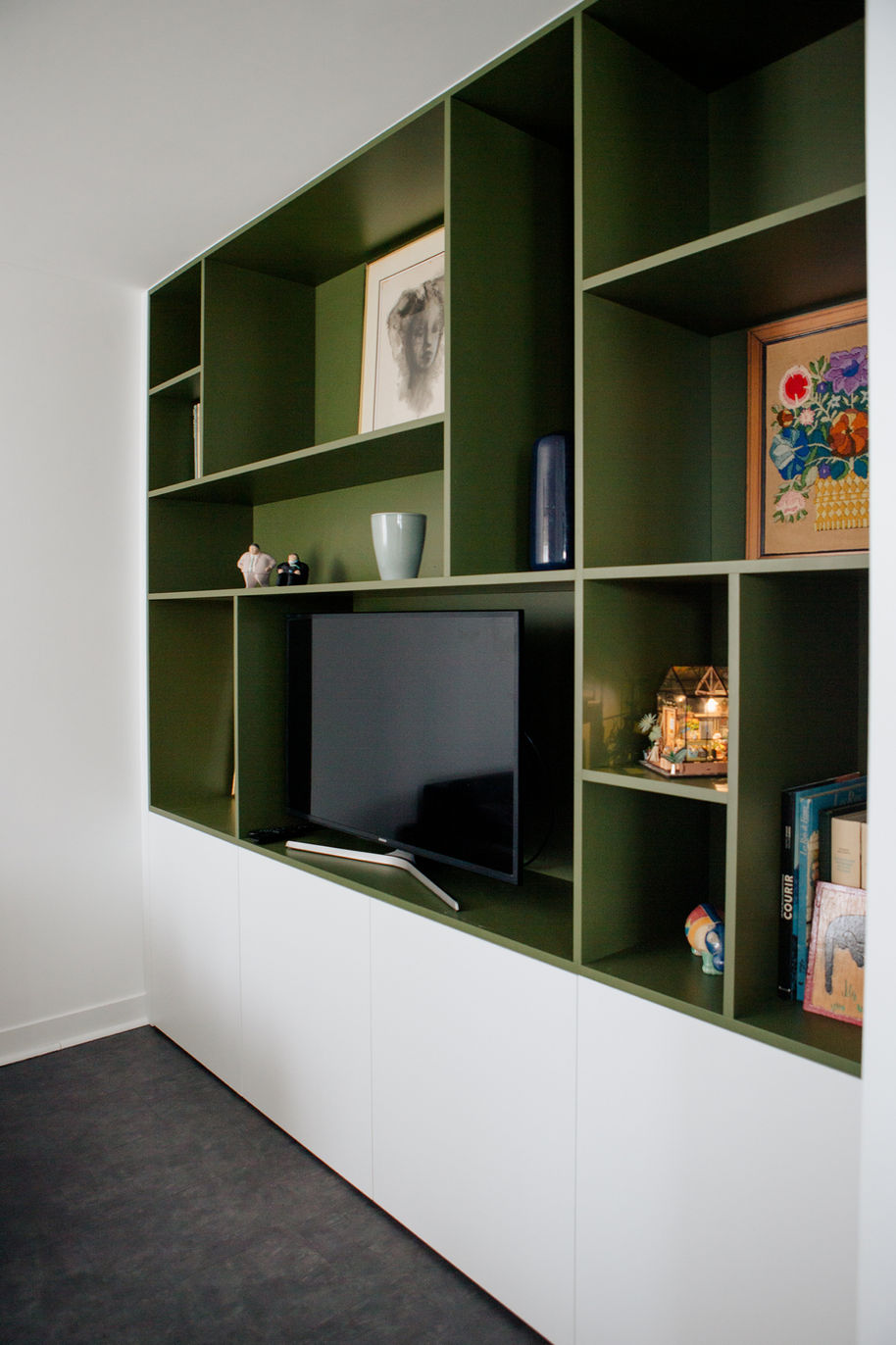 Ce meuble TV / bibliothèque sur mesure, a été pensé comme un élément architectural à part entière. Les niches graphiques, habillées d'un vert profond, structurent le mur et mettent en valeur objets décoratifs et oeuvres, tandis que les rangements bas blancs apportent légèreté et fonctionnalité. Un ensemble équilibré, à la fois élégant, contemporain et parfaitement intégré à l'espace de vie.