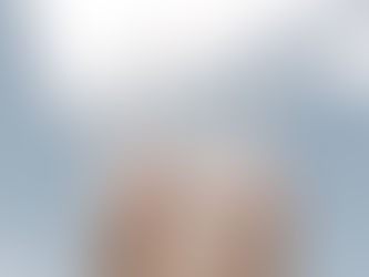 Hand hält ein Glas mit klarem Wasser gegen den Himmel, Sonnenlicht bricht sich im strukturierten Glas und erzeugt helle Reflexionen.