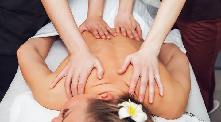 A woman enjoys a four hands massage at a massage spa