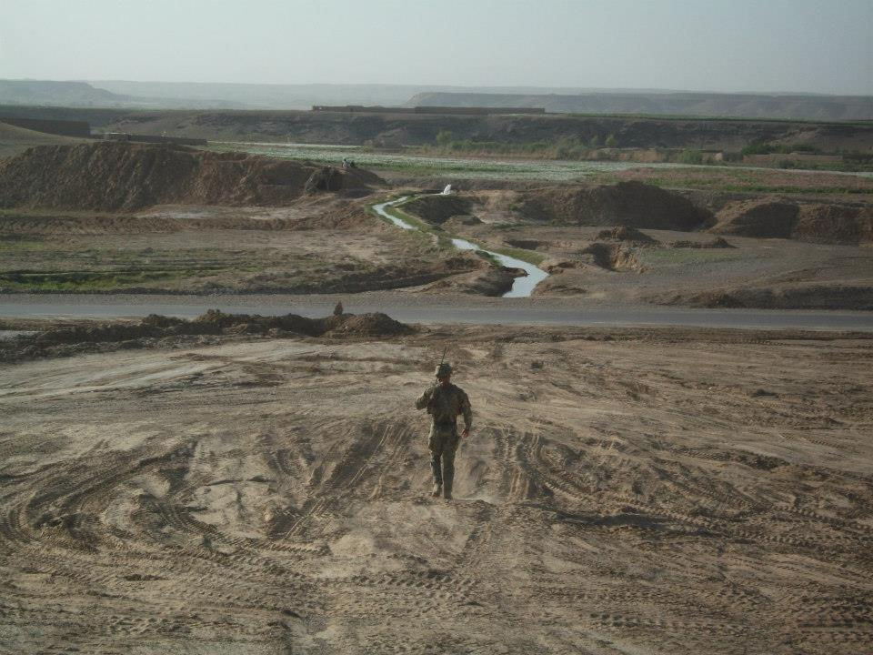 Soldat i Afghanistan går alene på en jord i sin militær udrustning