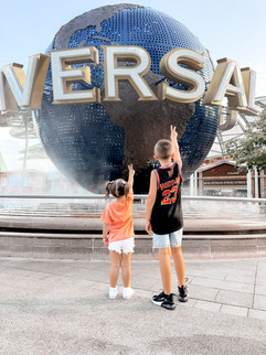 Kids doing peace sign in front of Universal Studios World ball in Singapore