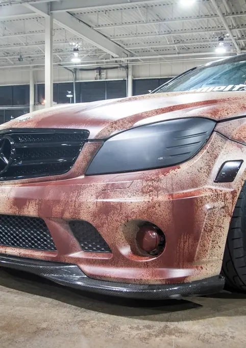 Custom Mercedes-Benz C-Class with rust-effect paint job in a garage.