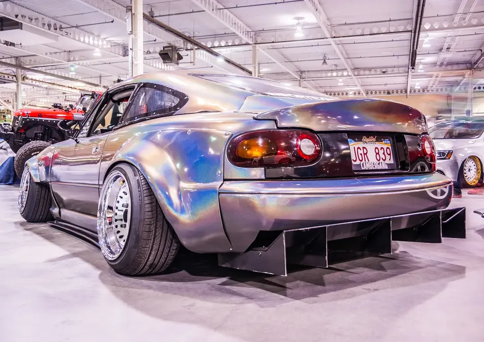 Customized iridescent widebody car QGR 878 with large rear diffuser.