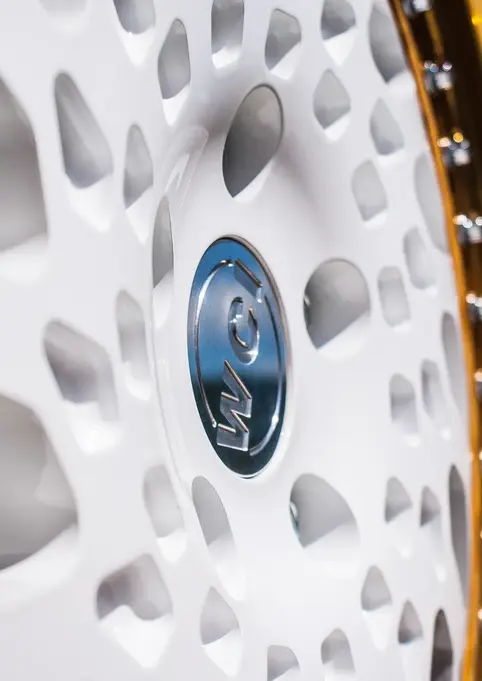 Close-up of a white and gold car rim with the logo details showing
