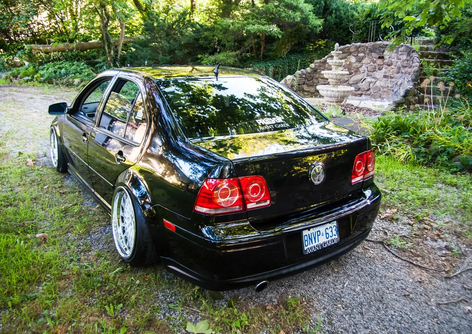 Black modified VW Jetta, license plate "GNP G3", parked on grass.