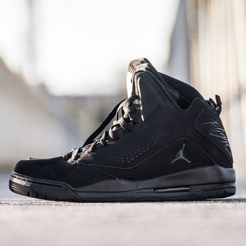 Black Jordan high-top sneaker with Jumpman logo on concrete outdoors.