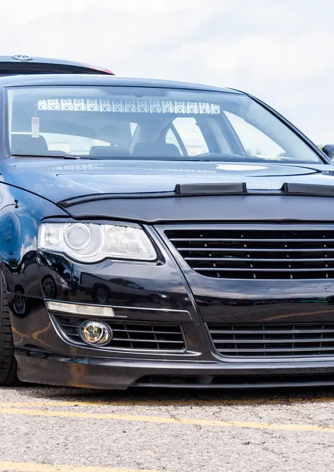 Modified black Volkswagen Passat with custom grille and lowered stance outdoors.