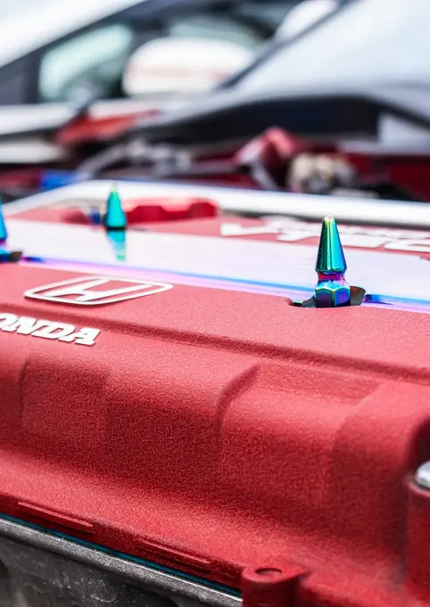 Red textured Honda engine cover with HONDA text and iridescent bolts.
