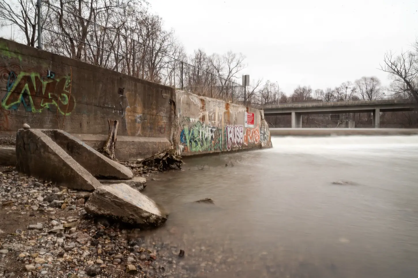 Cityscape & Street Fine-Art Photography by Blake Ferguson demonstrate the calm stream of the Thames River in Downtown, London, Ontario, surrounded by graffiti.