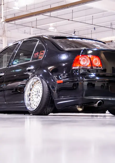 Black Volkswagen sedan at a car show with custom chrome wheels