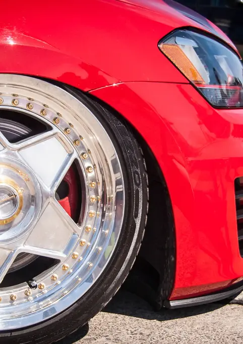 Red car's custom multi-spoke wheel and lowered suspension