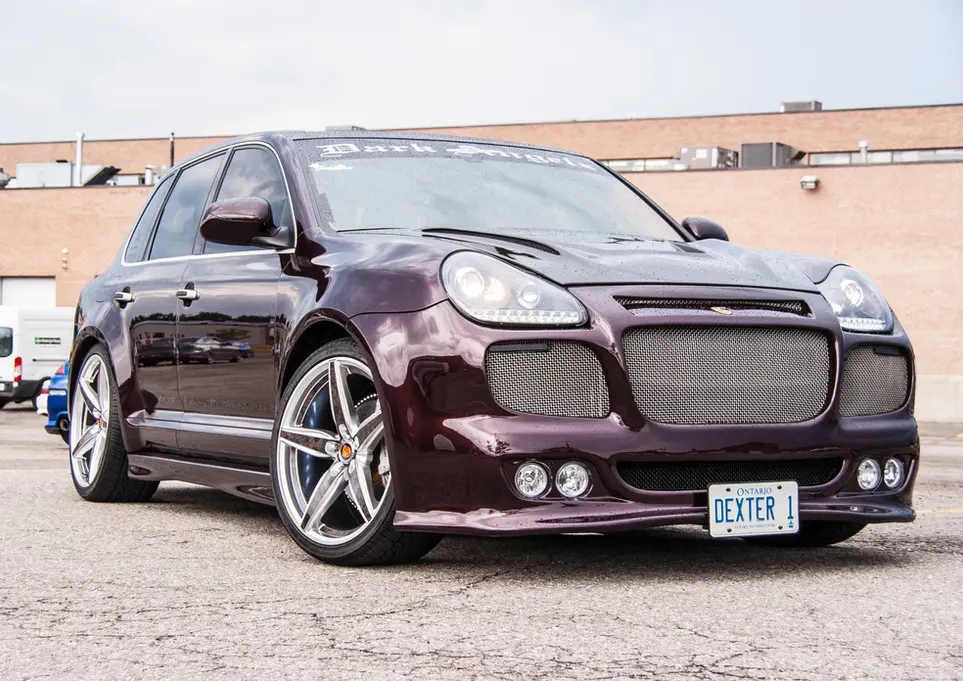 Customized dark red Porsche Cayenne SUV, DEXTEN license plate, aftermarket wheels.