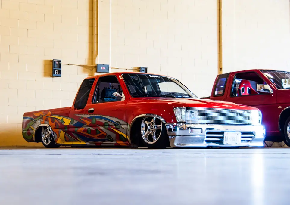 Slammed red custom pickup truck with vibrant flame graphics.