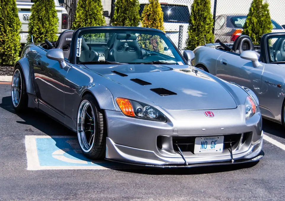 Silver convertible sports car in a parking lot with custom modifications.