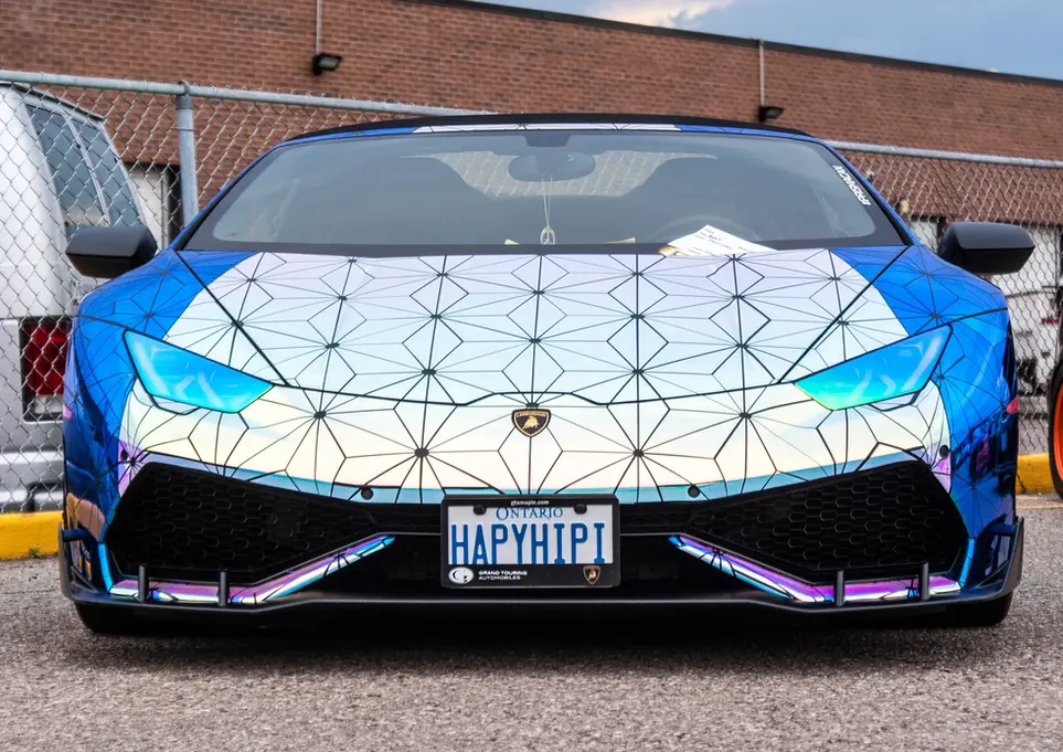 Front view of blue and white geometric patterned Lamborghini with 'HAPYHIP1' license plate.