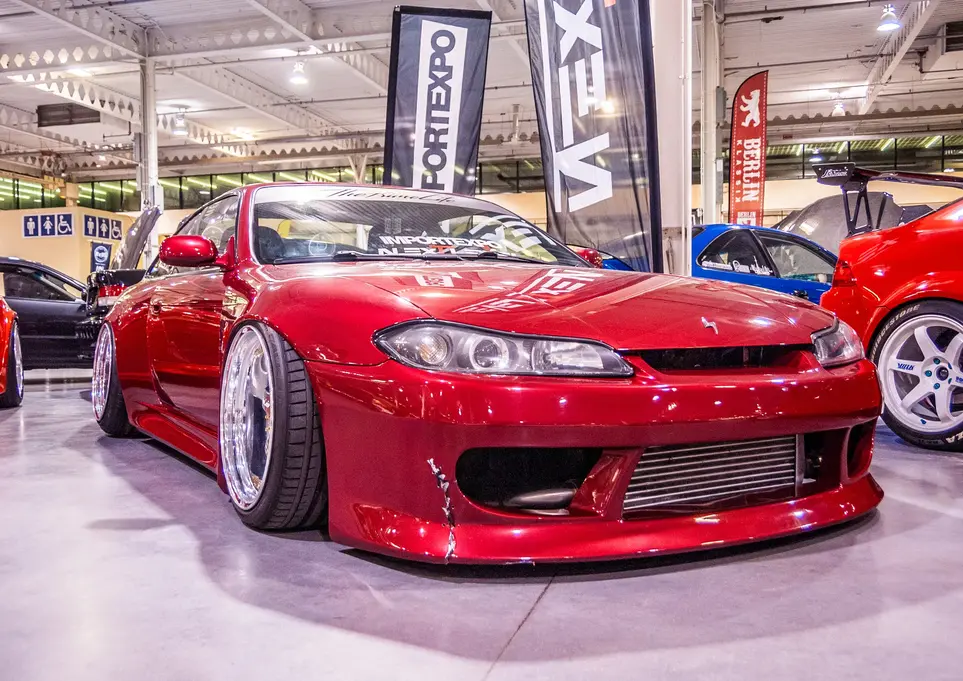 Red modified sports car, FORTEXPO VEX banners, indoor car show.