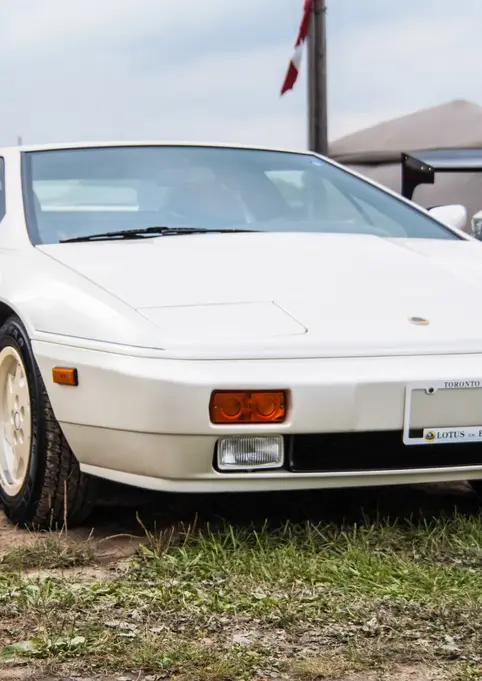 White Lotus Esprit sports car parked on grass at outdoor event.