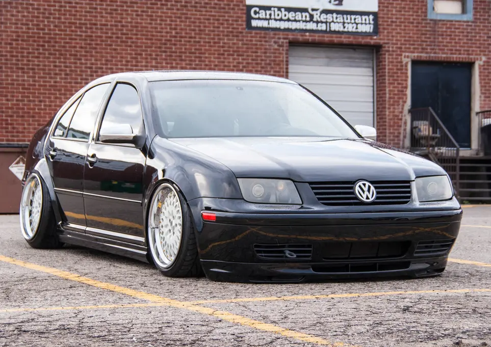 Black stanced Volkswagen Jetta parked near Caribbean Restaurant building.