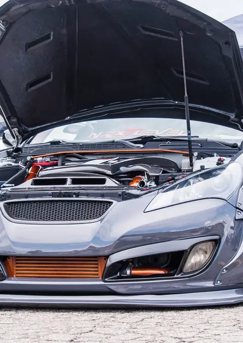 Aggressive gray modified sports car with hood open, orange accents.