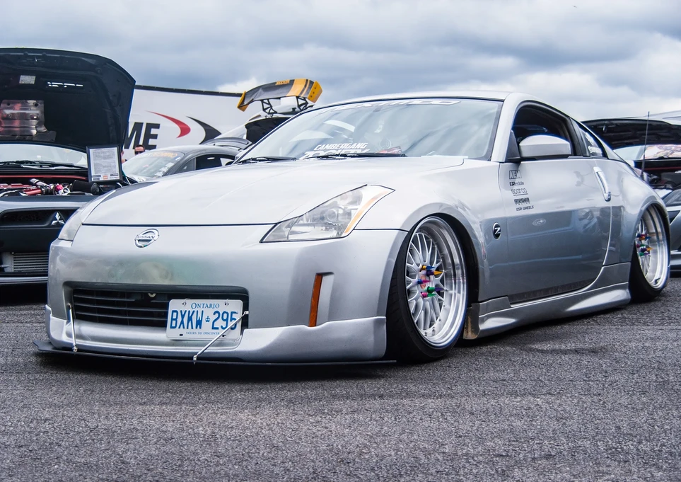 Silver Nissan 350Z stanced car, license plate BXKW 295, at outdoor show.