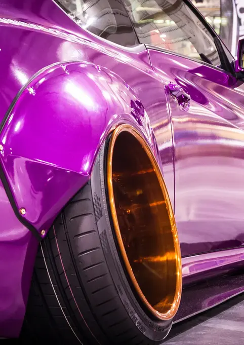 Purple custom widebody car with large gold wheels at a car show.