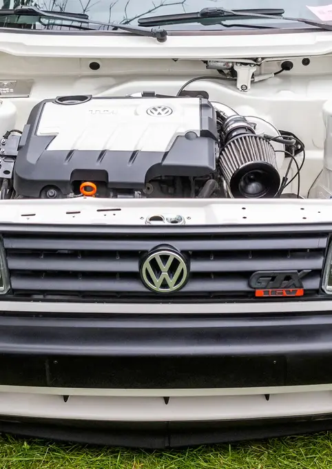 White Volkswagen car, open hood, Volkswagen logo, GTI, on green grass background