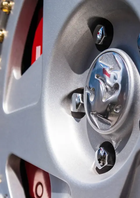 Close-up of a silver car wheel with gold accents and logo details.