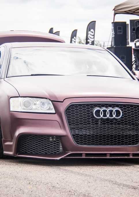 Custom maroon Audi sedan, low-rider stance, at outdoor car show.