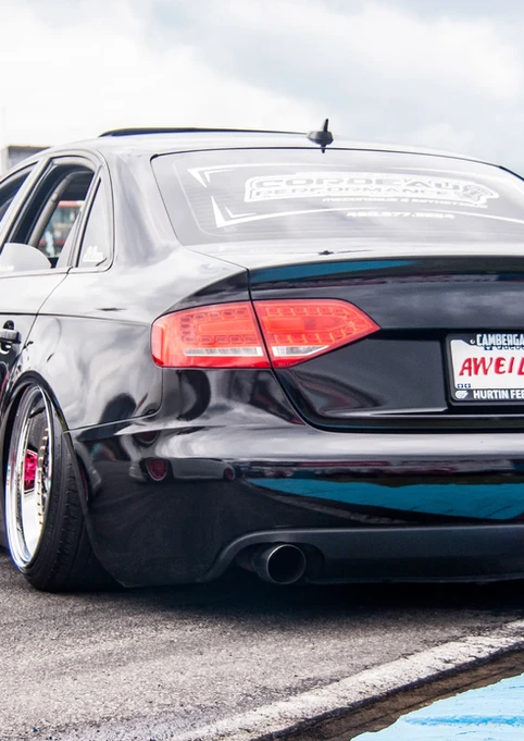 Black stanced Audi A4 "MR. KLUTZ" license plate on track.