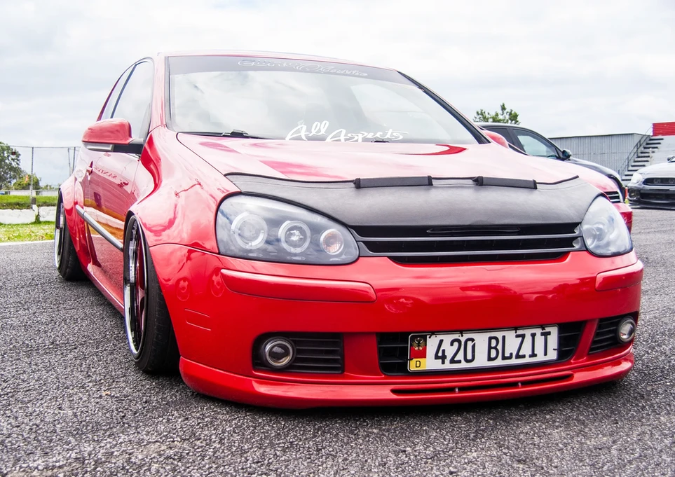 Red modified Volkswagen Golf car with "420 BLZ1T" license plate.