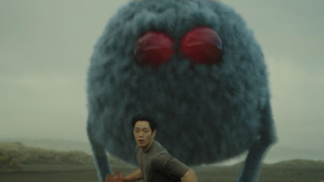 a man stands in front of a fluffy monster with red eyes