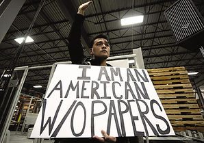 young man holds sign reading i am an american without papers