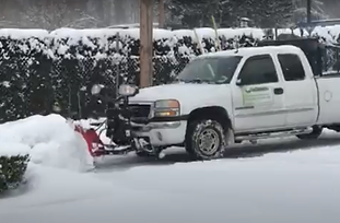 Earthworks Landscape Services truck plowing snow after a storm in Seattle.