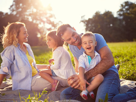 a family sitting on a blanket in a park on a sunny day enjoying their time together