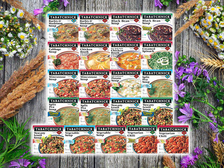 21 varieties of Tabatchnick soups overlaid on a wood background with purple and white flowers around them