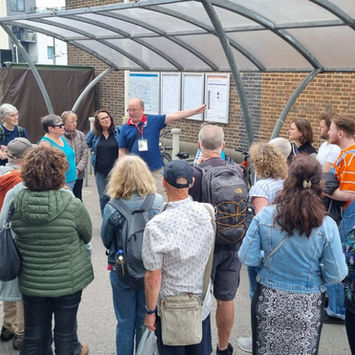 a group listens to a speaker tell some local history at forest hill station
