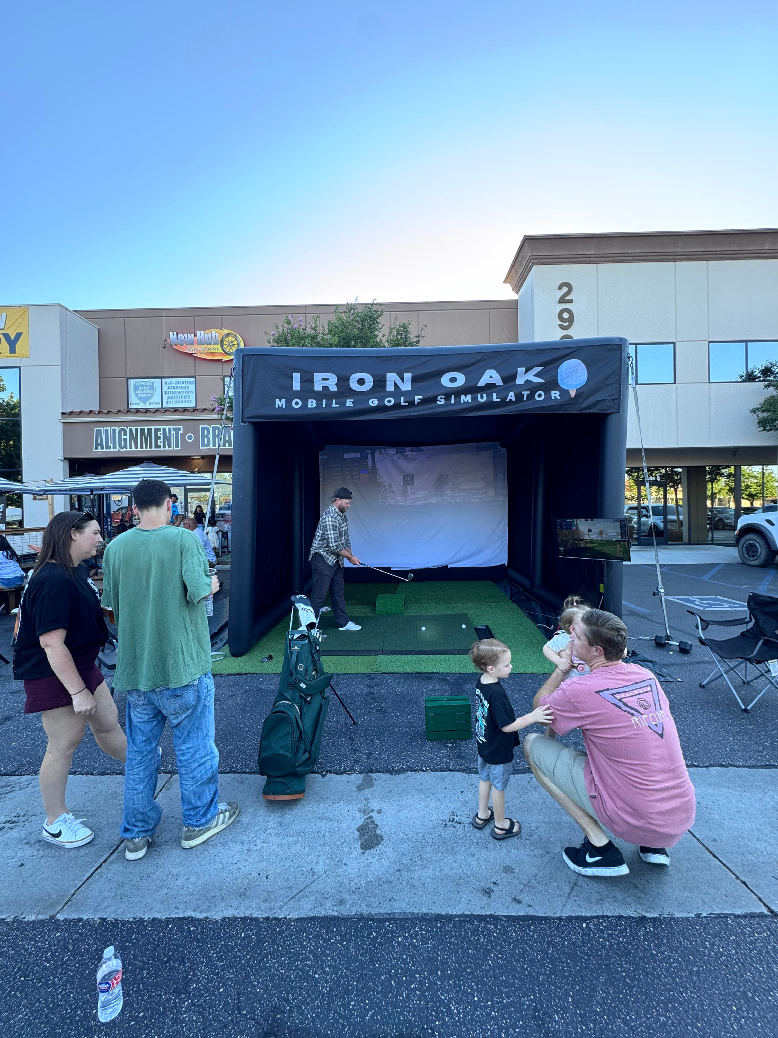 Outdoor golf simulator setup with friends, food, and drinks at a venue.