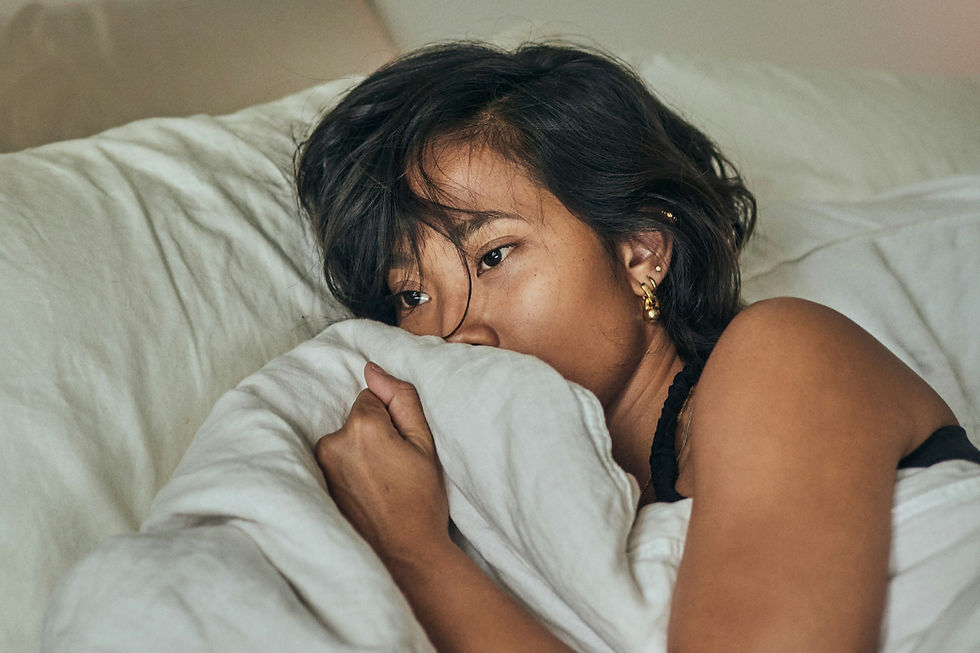 a young woman in bed wondering if she is experiencing period or pregnancy symptoms