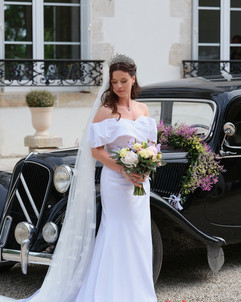 La mariée pose devant une vielle voiture noire