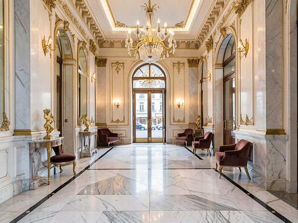 Hall élégant avec sol en marbre, lustre et moulures dorées.