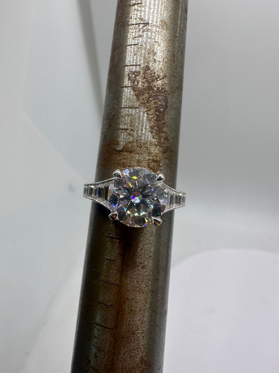 Thumbnail: 3 carat round moissanite with graduated trapezoids on a milgrain band 