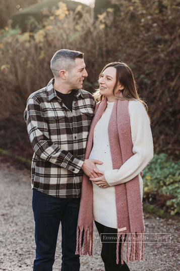 Couple looking at each other and holding mum's baby bump