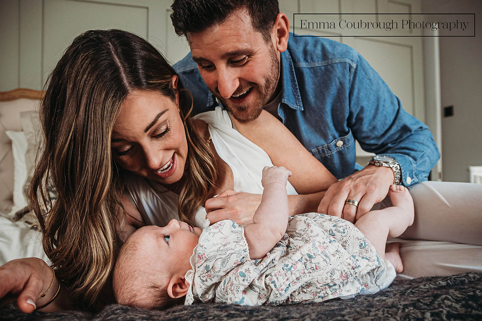 Baby lying on bed with her parents