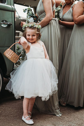 Flower girl in white dress holding confetti basket