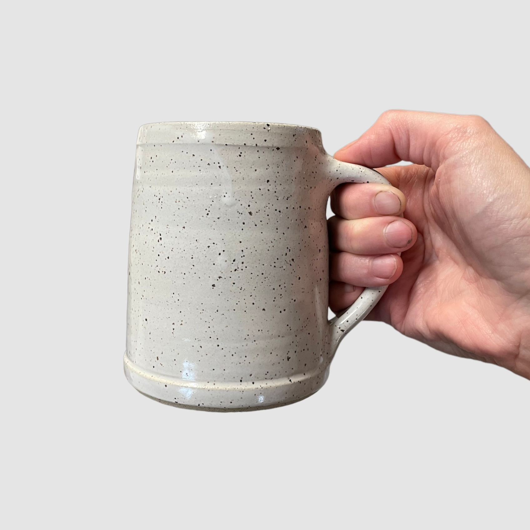 Hand holding a 16oz speckled ceramic stein mug