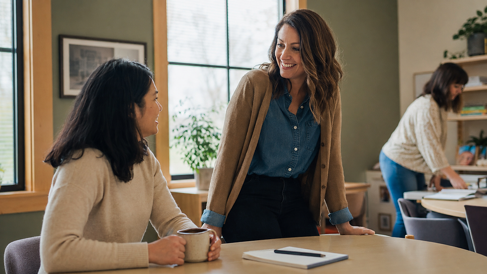 Two women talking in a modern office during a career break.