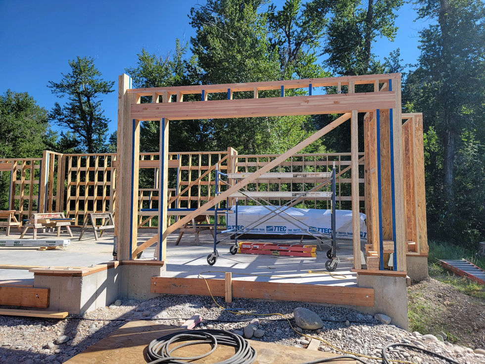 Framed bay with a heavy diagonal brace and rolling scaffold inside, built on a concrete stem wall