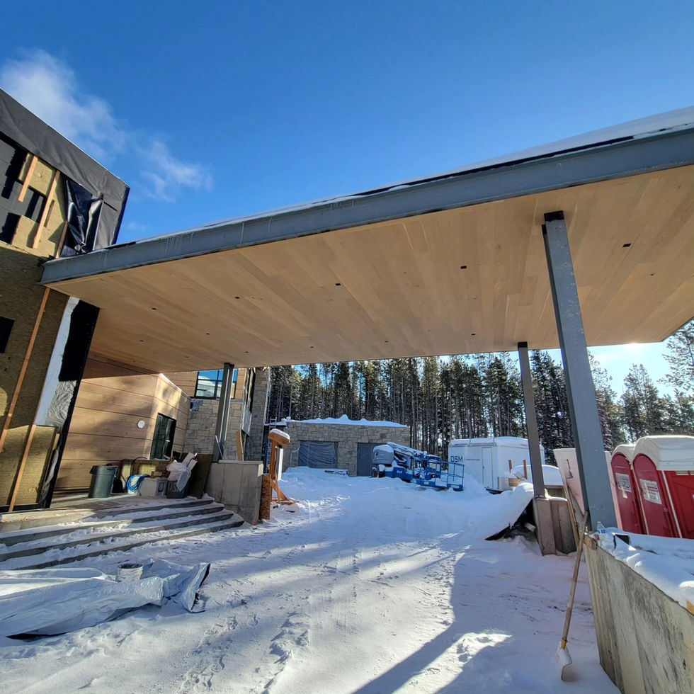 Large wood soffit projecting over the snow-covered entry with the timber walls still under weather protection